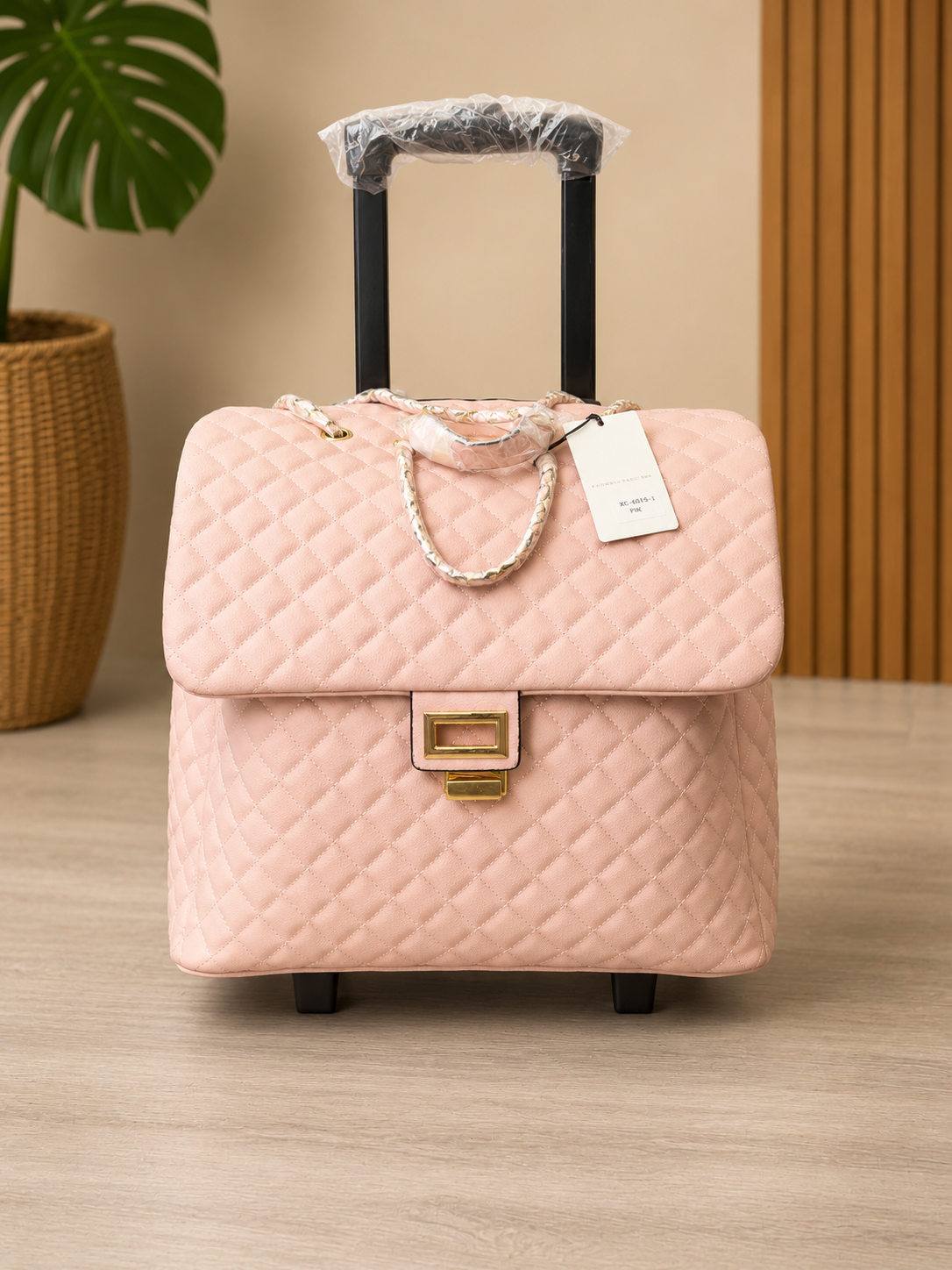 Pink quilted suitcase with a tag on a wooden floor.