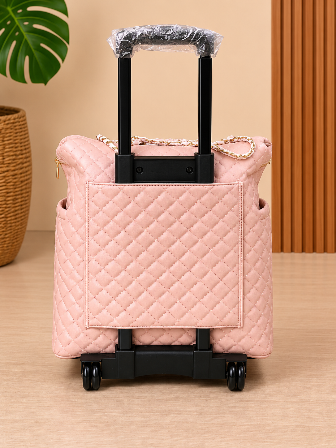 Pink quilted suitcase with black handle and wheels on a beige surface.