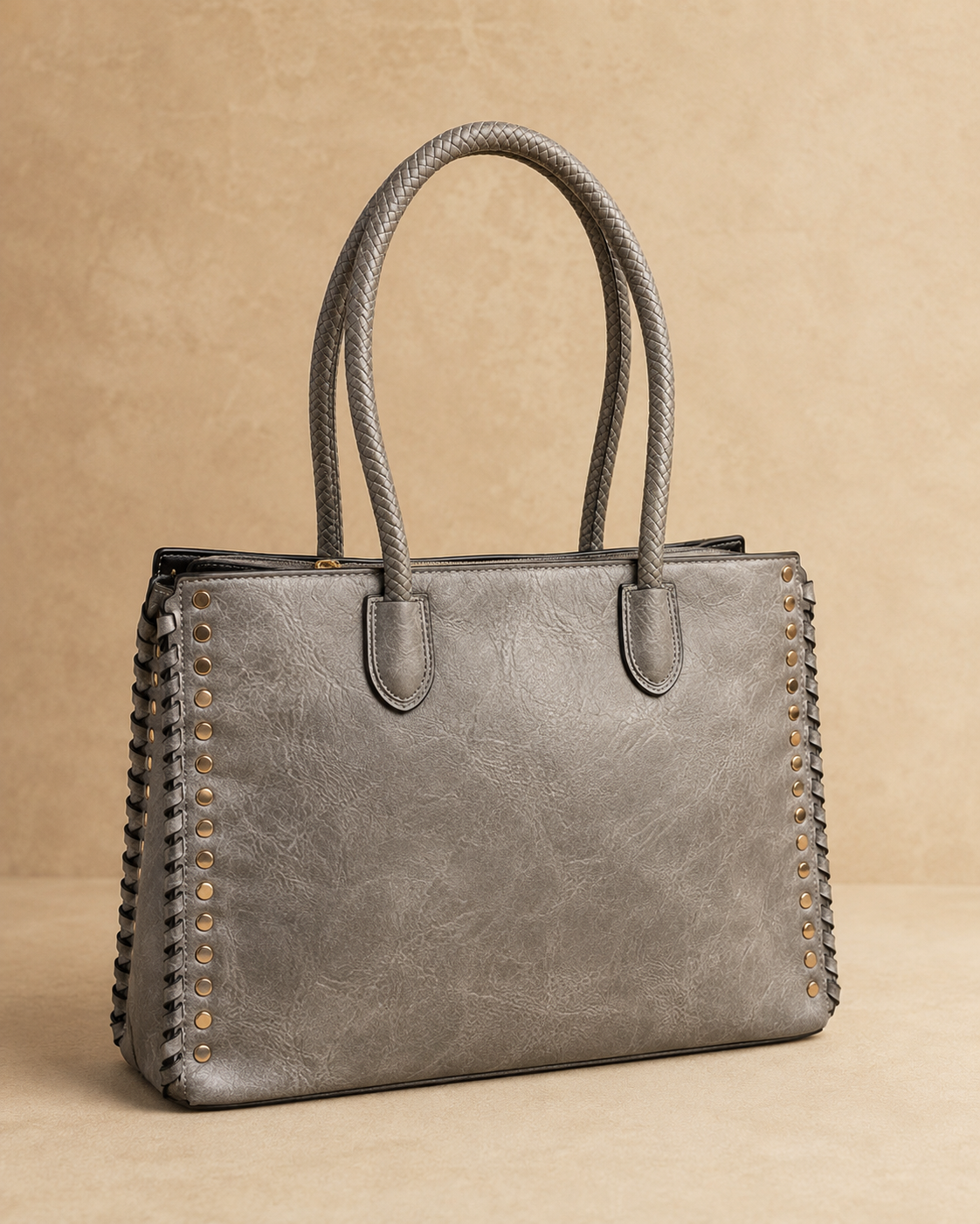 Gray handbag with studded details on a beige background
