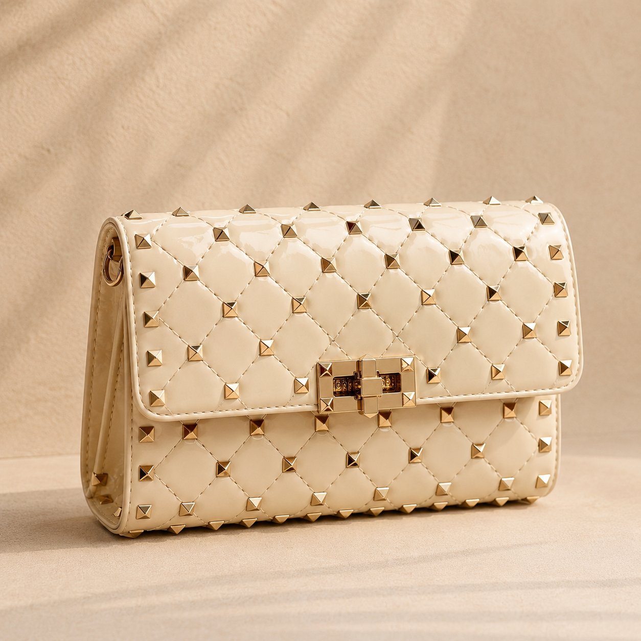 Beige quilted handbag with gold studs on a beige background