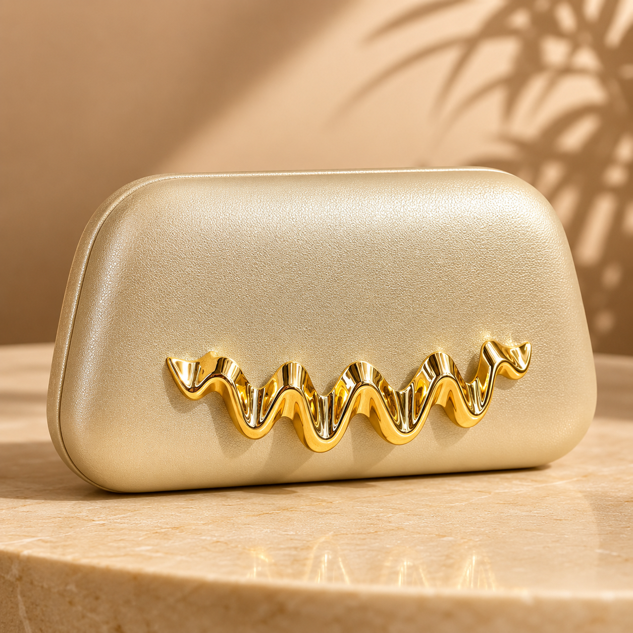 Gold clutch bag with decorative gold accents on a beige surface