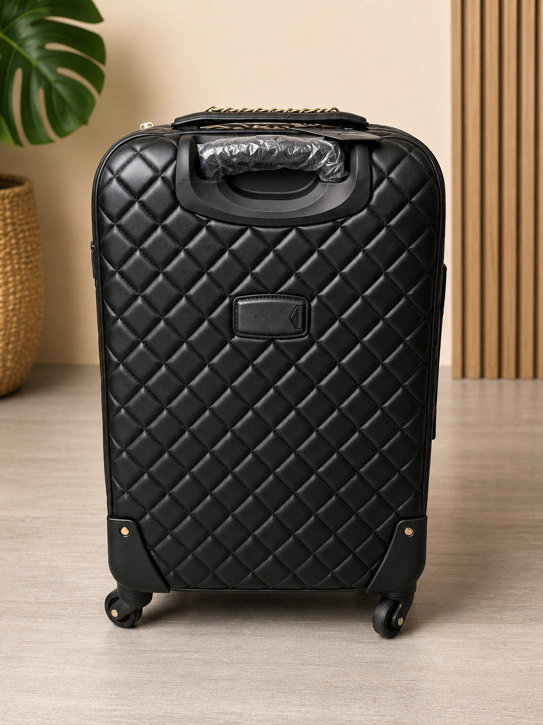 Black quilted suitcase on a wooden floor with a neutral background