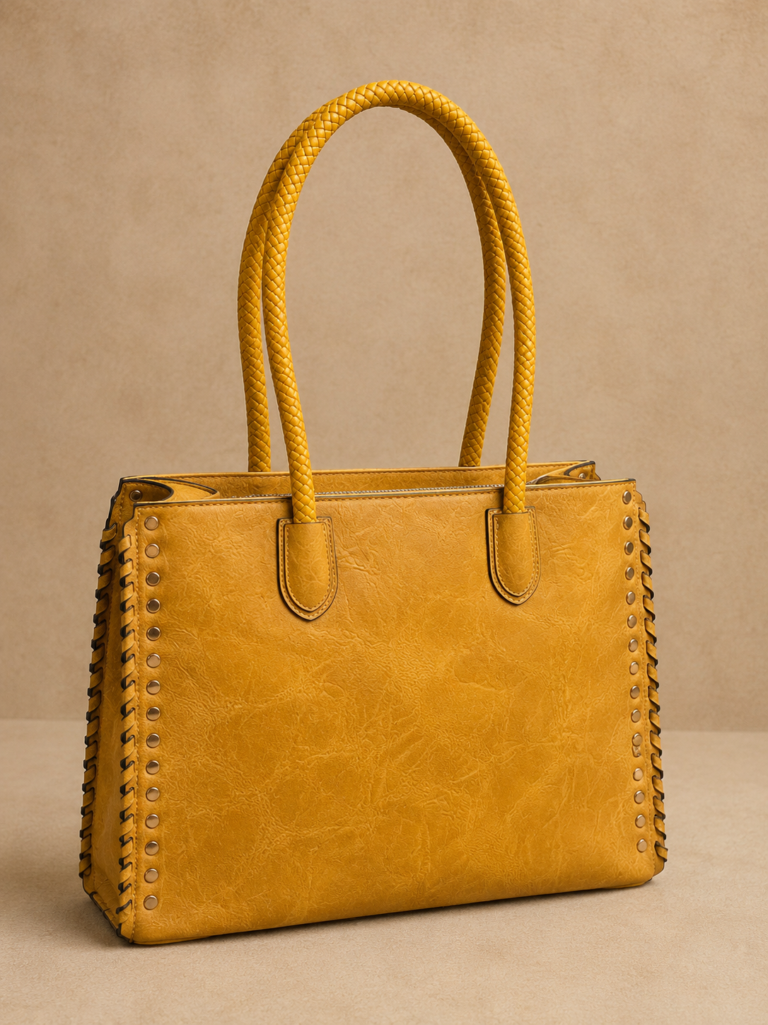 Yellow handbag with studded details on a beige background
