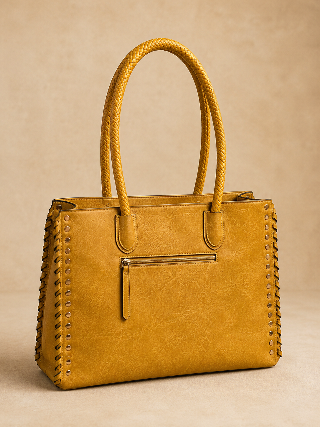 Yellow handbag with studded details on a beige background