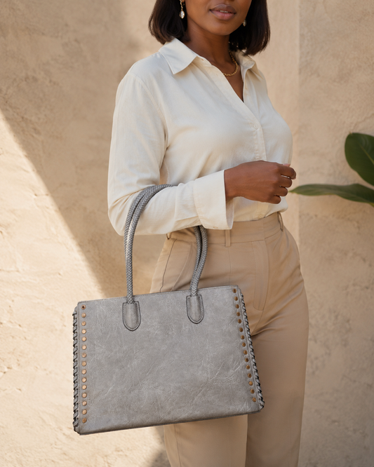 Woman holding a gray handbag against a beige wall