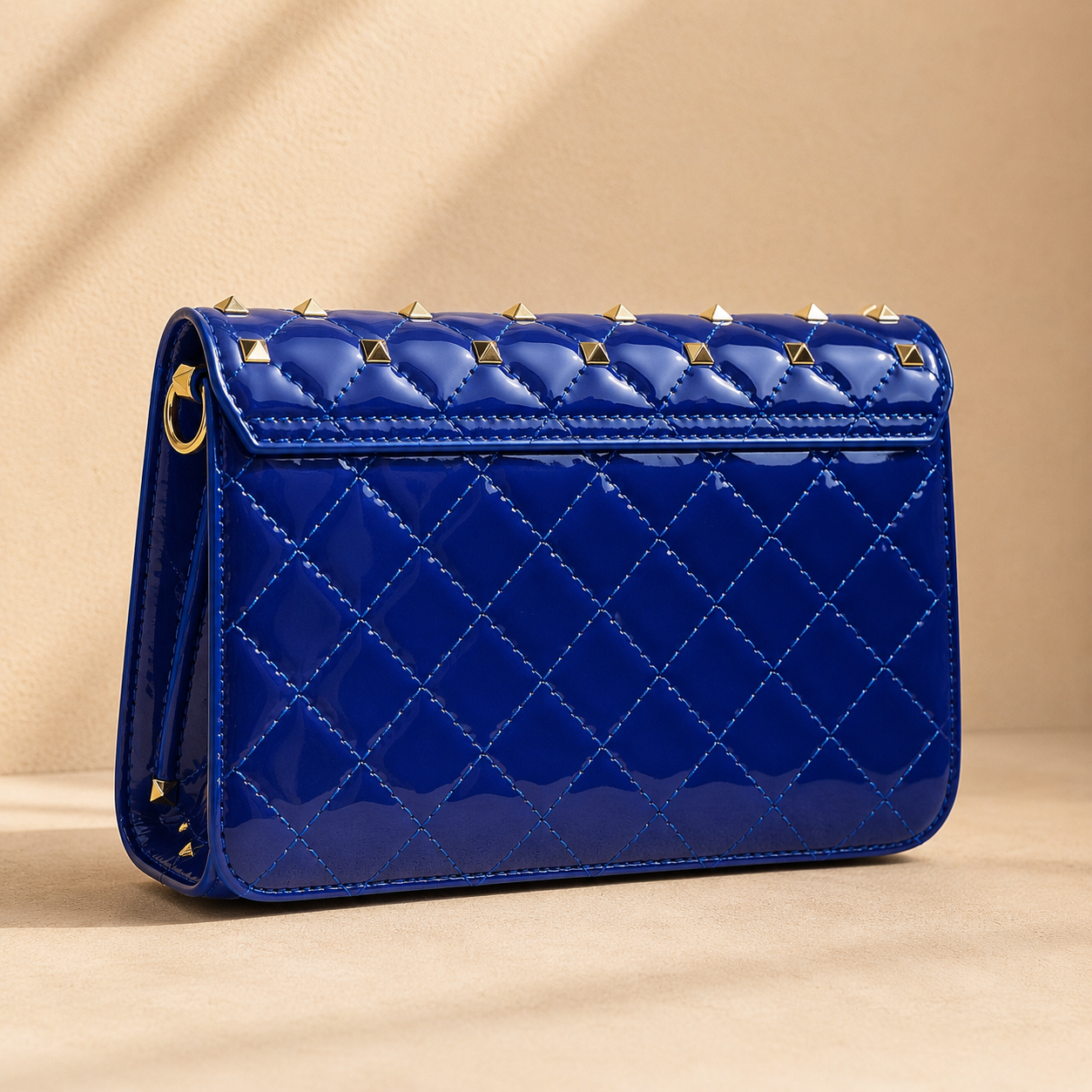 Blue quilted handbag with gold accents on a beige background
