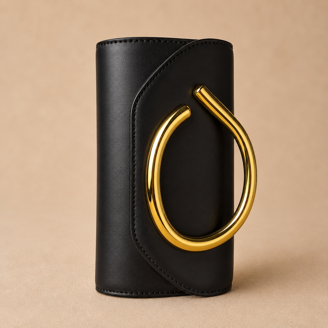 Black leather clutch with a gold handle on a beige background