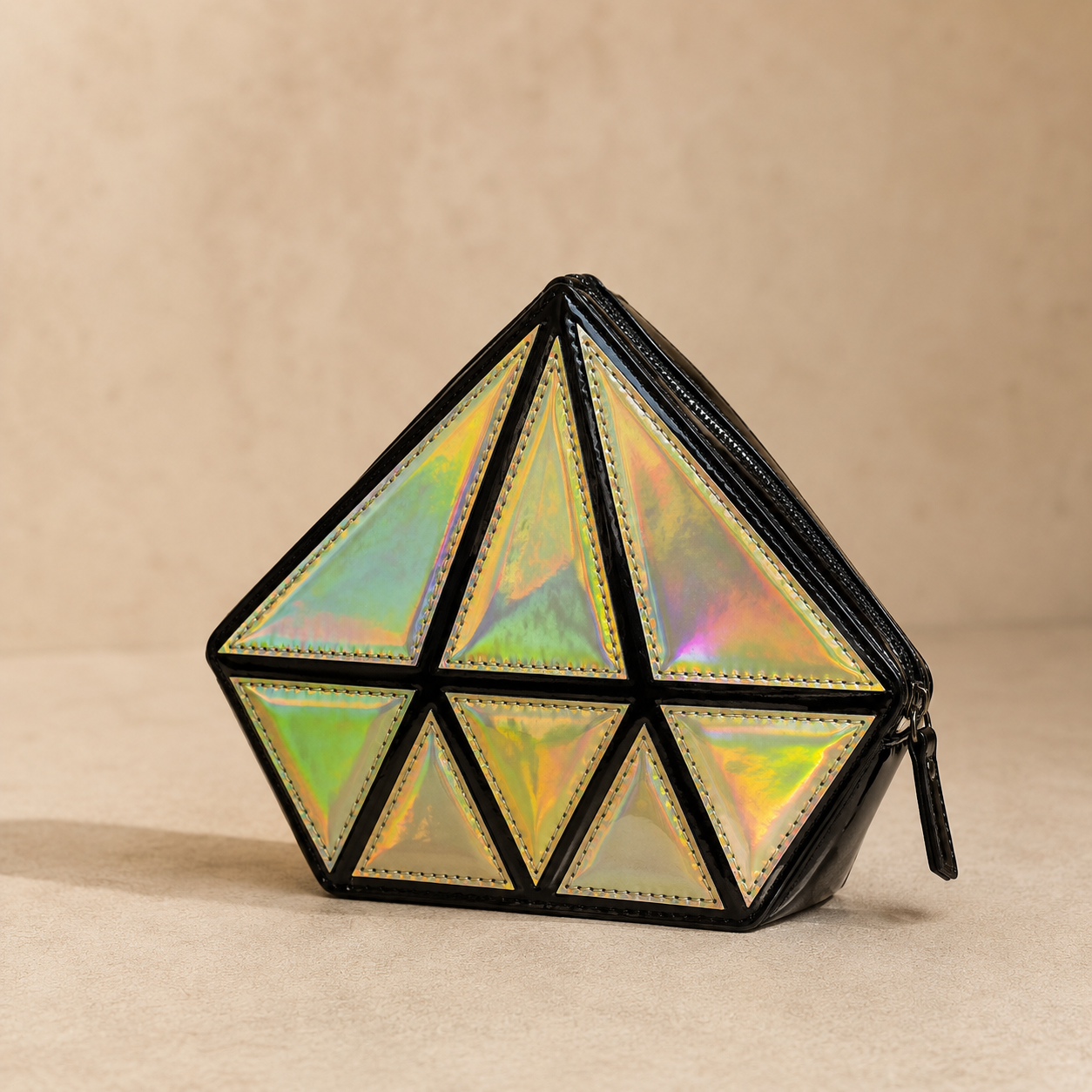 Geometrically shaped clutch with iridescent panels on a beige background