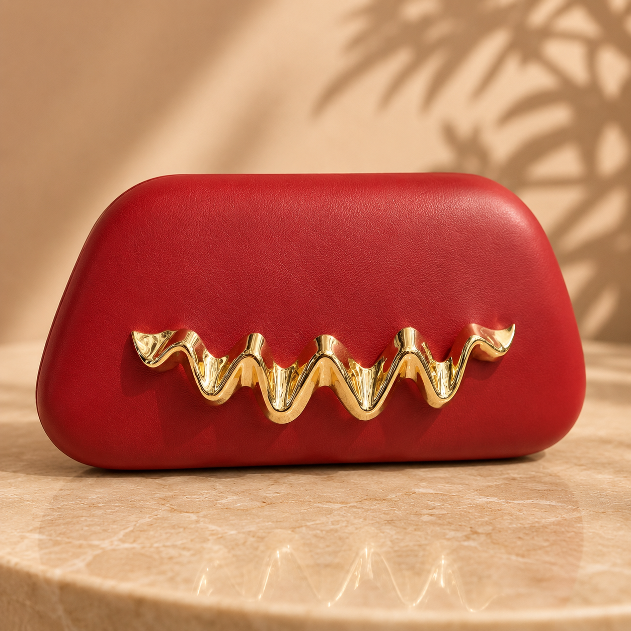 Red clutch with gold embellishment on a beige surface