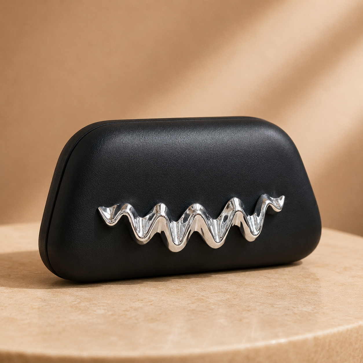 Black clutch with a silver wavy accent on a beige background