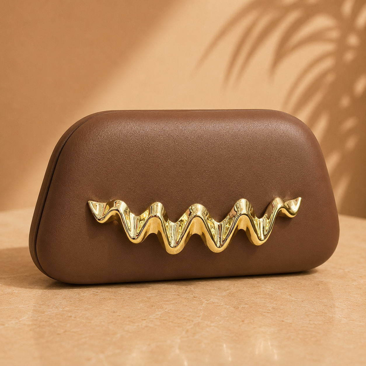 Brown clutch with gold decorative handle on a beige background
